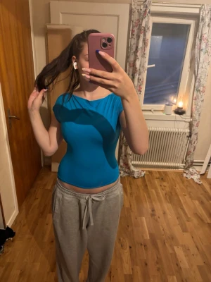 Blå tight topp med öppen rygg - Säljer en blå tight topp med korta ärmar och öppen rygg. Toppen är croppad och har en enkel, stilren design som passar perfekt till jeans eller kjol. Materialet känns mjukt och stretchigt, troligen polyester eller bomullsmix.
