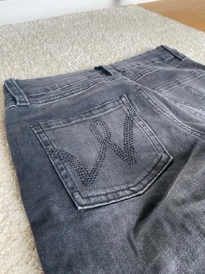 Grå svarta jeans, low waist - Snygga svarta jeans från Gina Tricot med glitter detaljer på bakfickan. Low waist