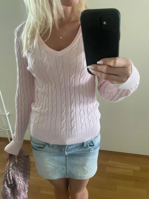 Ljusrosa kabelstickad tröja från Gant - Supersöt ljusrosa kabelstickad tröja från Gant med v-ringning och långa ärmar. Tröjan har ribbade muddar och liten broderad logga på bröstet. Perfekt nu till sensommar och höst! Tveka inte att skriva till mig om frågor eller prisförslag! 