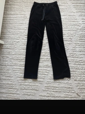 Svarta mjukisbyxor i sammet - Mysiga svarta mjukisbyxor med raka ben och snörning i midjan. Perfekta för chill dagar hemma eller när du vill vara extra bekväm. Klassisk modell utan synliga loggor eller detaljer.