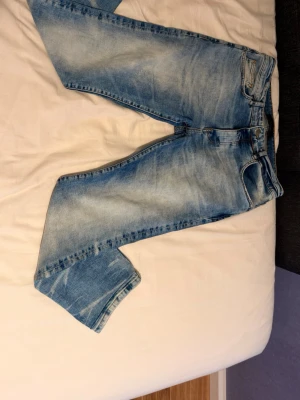 Amiri jeans ljusblå - Säljer ett par ljusblå jeans med raka ben och snygga slitningar. Jeansen har klassisk femficksmodell, normal midja och är tillverkade i denim. Perfekta för en avslappnad och trendig look.