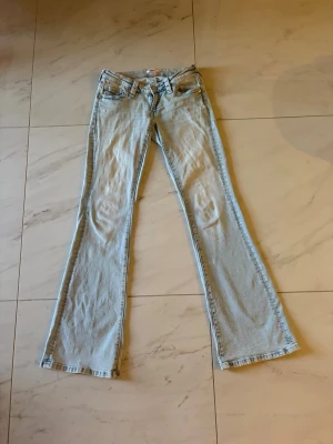 Ljusblå bootcut jeans med W-detalj - Ett par ljusblå bootcut jeans med slitna W-detaljer på bakfickorna. 