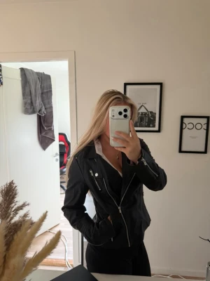 Skinnjacka - En svart skinnjacka med silvriga detaljer, även med rosa foder inuti. Det är en lite tjockare jacka så den håller värmen. Aldrig använt prislappen kvar, från only i storlek 38