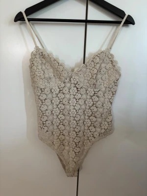 Body  - Supersöt beige body med blommönster, virkat material och luftig, justerbara band. Som man ser på sista bilden har nån liten tråd gått upp men annars är den i toppenskick och inte använd särskilt många gånger. Skriv vid frågor🥰