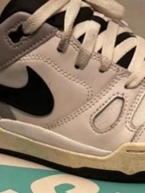 Nike vita och svarta sneakers - Säljer ett par vita och svarta Nike sneakers med klassisk swoosh på sidan. Skorna har vita snören, svart yttersula och detaljer i svart på ovandelen. Tillverkade i läder med perforerade partier för ventilation. 