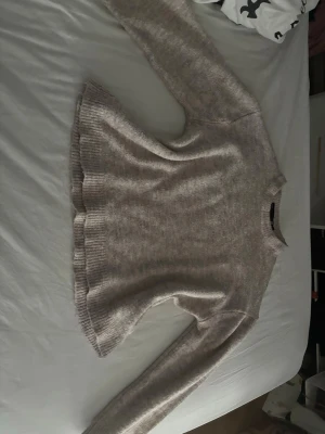 Beige stickad tröja med rund hals - Mysig beige stickad tröja med rund hals och långa ärmar. Tröjan har ribbstickade muddar vid ärmslut och nederkant samt en lätt utsvängd passform. Perfekt för lager på lager under kyliga dagar. Skulle mer säga tt det är storlek xs men på lappen står det S.