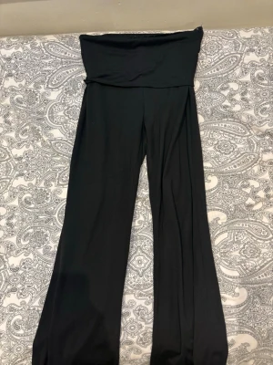 Svarta bootcut leggings med hög midja - Säljer ett par svarta leggings med bootcut-ben och hög, vikbar midja. De är stretchiga och mjuka, perfekta för en chill och avslappnad stil. Passar lika bra till oversized hoodie som till crop top. Materialet känns som bomullsmix med lite elastan.