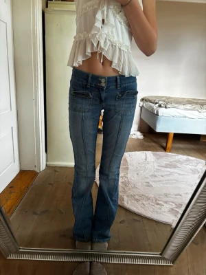 Blå bootcut jeans med fickor - Jeans från Nelly. Storlek 34 ( XS ). Använda och är lite slitna längst ner på byxorna. Tror ej att dessa säljs i butik längre. 
