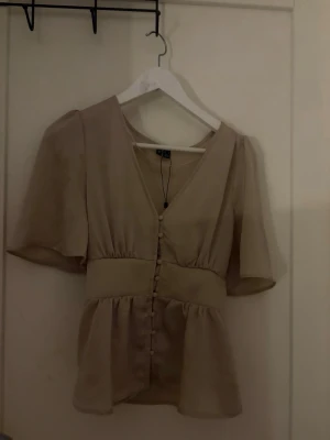 Beige blus med knappar och v-ringning - Jätte fin blus säljer på grund av att den inte kommer till användning!💕