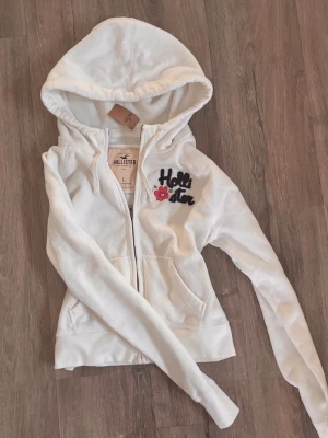 Ny hollister zip  - Helt ny vit hollister zip tröja/kofta med så mjuk fluffig insida! Med rosa tryck och prislappen kvar! Stl L men väldigt liten i storlek, passar mig som har xs/s🌸🌸