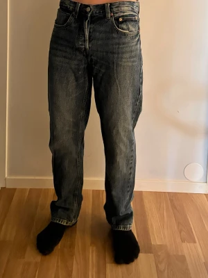 Blå raka jeans med hög midja | Zara - Säljer ett par klassiska blå jeans med rak passform och hög midja. Jeansen har fem fickor, knappgylf och snyggt slitna detaljer för en avslappnad look. Perfekta till vardags och passar till det mesta i garderoben.