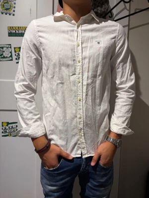 Vit skjorta från Gant - Klassisk vit skjorta från Gant i linne med knappar framtill och diskret logga på bröstet. Skjortan har lång ärm och normal passform, perfekt till jeans eller chinos för en clean look.