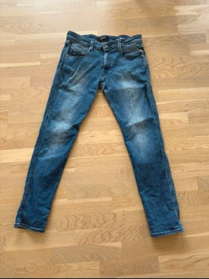 Replay anbass - Snygga blå slim fit jeans med lätt slitna detaljer och klassisk femficksdesign. Jeansen har normalhög midja och smala ben. Materialet ser ut att vara bomullsdenim med stretch för extra komfort. Perfekta för en avslappnad och trendig look.
