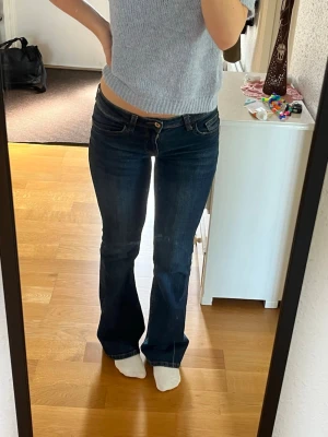 Lågmidjade bootcut jeans  - Superfina mörklblå bootcut jeans med låg midja och broderi på bakfickorna! 💙 de är sparsamt använda och är endast lite slitna vid byxbenets nedre kant (se sista bilden). De sitter perfekt på mig som är 165 cm lång ☺️Strl 36. 