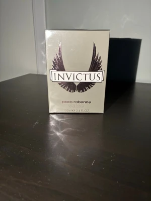 Paco Rabanne Invictus EdT 100ml - Paco Rabanne Invictus Eau de Toilette i 100ml flaska. Förpackningen är silverfärgad med svart logga och vingar på framsidan. En ikonisk herrdoft som kommer i en stilren och modern kartong, perfekt för dig som gillar fräscha och maskulina parfymer.