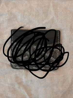 Guyard plånbok  - Snyggt svart kortfodral med vitt mönster och kontrastsömmar. Fodralet har en kompakt och smidig design, perfekt för kort och småsedlar. Materialet ser ut att vara konstläder eller läder.