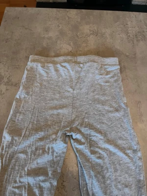 Grå mjuka leggings - Ett par enkla och bekväma leggings i ljusgrått. De har en hög midja och är tillverkade i ett mjukt, stretchigt material som sitter skönt mot kroppen. Perfekta för en avslappnad stil eller som basplagg till olika outfits.