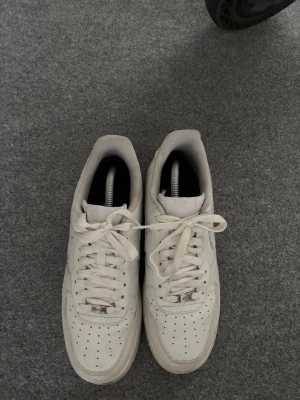 Air Forces - Snygga vita sneakers med lågt skaft och klassisk siluett. Skorna har perforerad tå, vita skosnören och detaljer i vitt. Tillverkade i läder med en vit sula och diskreta sömmar längs sidan. Perfekta för en clean och stilren look.