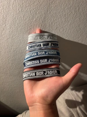 Dior tygarmband - Säljer flera Christian Dior J'Adior tygarmband i olika färger som grått, blått och svart. Armbanden har broderad text och är justerbara för att passa de flesta handleder. Perfekt accessoar för att lyfta din outfit med en lyxig touch. 1 för 169 , 2 för 279, 3 för 319