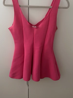 Rosa ärmlös linnetopp - Snygg rosa linnetopp med v-ringning och utsvängd passform. Toppen är ärmlös och har en enkel, stilren design som passar perfekt till jeans eller kjol. Materialet känns mjukt och följsamt mot kroppen.
