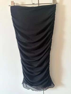 Gina tricot svart midi kjol i mesh  - Svart midi kjol från gina tricot i storlek S. Kjolen är tajt och går precis nedanför knäna. Rynkat tyg i mesh med en tajt underkjol som gör att den ej är genomskinlig. Resår i midjan. Använd vid ett tlllfälle så mycket bra skick. 