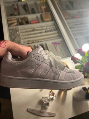 Grå Adidas Campus sneakers - Snygga grå Adidas Campus sneakers i mocka med klassiska vita ränder på sidan och breda vita skosnören. Låg modell med diskret Adidas-logga på plösen och sidan. Perfekta för en clean och stilren look. Nypris 1099