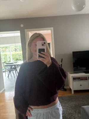 Vinröd croppad stickad tröja - Mysig vinröd stickad tröja med croppad passform och vida ärmar. Tröjan har en lös siluett och bred halsringning som kan bäras off-shoulder. Perfekt för dig som gillar en avslappnad och trendig stil. Använd 1 gång och och det är bara att fråga ifall ni undrar några frågor!💗