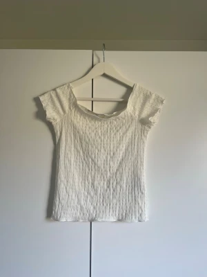 Vit ribbad topp med kort ärm - Säljer en enkel och stilren vit ribbad topp med korta ärmar och rund hals. Toppen har en smickrande passform och är perfekt att matcha med jeans eller kjol. Materialet känns mjukt och stretchigt.