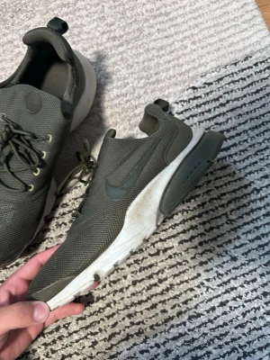 Mörkgröna Nike sneakers mesh - Snygga mörkgröna Nike sneakers med ovandel i mesh och vita sulor. Skorna har klassisk låg profil, rund tå och snörning framtill. Perfekta för en sportig och avslappnad stil.