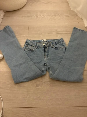 Ljusblå bootcut jeans - Säljer ett par ljusblå bootcut jeans med klassisk femficksmodell och låg midjade. Jeansen har dragkedjegylf och knapp framtill. Materialet är denim i bomull och passformen är rak upptill med utsvängda ben. Dom är bootcut och är från Gina Young i storlek 152
