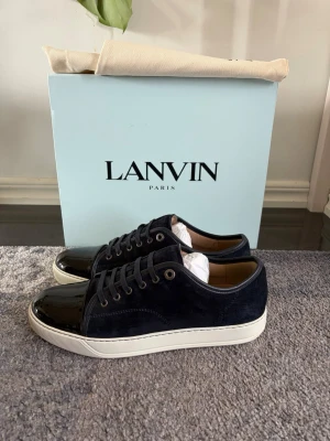 Mörkblå sneakers från Lanvin - Snygga mörkblå sneakers från Lanvin(43) köpta på Care of Carl. Skorna är nästintill oanvända med inga tecken på användning förutom lite smuts därpå sulan. Allt på bilden medföljer 