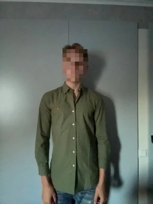 Olivgrön skjorta från Ralph lauren - Snygg olivgrön skjorta med klassisk krage och vita knappar hela vägen framtill från Ralph lauren. Skjortan har lång ärm och en liten broderad detalj på bröstet. Perfekt till jeans för en clean och stilren look. Storlek S