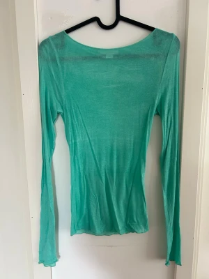 Turkos långärmad topp Gina Tricot - Säljer en tunn, turkos långärmad topp från Gina Tricot i storlek XS. Toppen har en rund halsringning och är gjord i ett lätt, stretchigt material som sitter snyggt på kroppen. Perfekt att styla lager på lager eller bära som den är. Endast använd 2 ggr