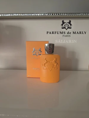 Parfums de Marly Perseus 125ml - Parfums de Marly – Perseus Eau de Parfum 125 ml Upplev den eleganta och kraftfulla doften av Perseus, skapad för den självsäkra, moderna mannen. Friska citrusnoter i toppen, kryddigt hjärta med salvia och kardemumma, samt varm bas av cederträ, amber och vanilj ger ett minnesvärt intryck. Elegant flaska i orange med hästreliefer. Princip full, perfekt för samlare eller lyxig doftgarderob. 📦 Snabb leverans – skickas samma dag (om ej hinder).