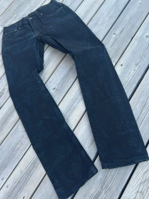 Svarta raka jeans från Nudie Jeans - Snygga svarta jeans från Nudie Jeans med raka ben och klassisk femficksmodell. Jeansen har en cool tvättad look och är tillverkade i slitstarkt denimtyg. Perfekta för dig som gillar en avslappnad men stilren vibe.