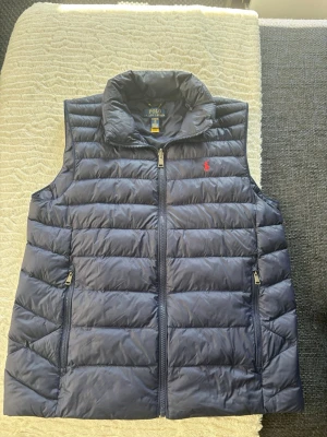 Mörkblå dunväst från Polo Ralph Lauren - Snygg mörkblå dunväst från Polo Ralph Lauren. Den är väldigt skön och bra passform men börjar tröttna. Kom med bud och frågor