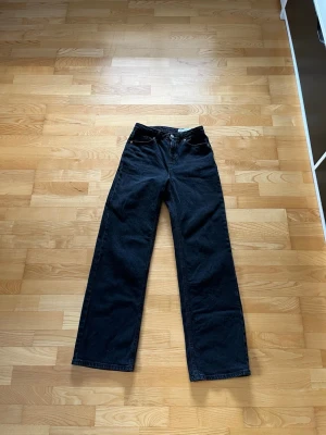 Svarta raka jeans från Vero Moda - Säljer ett par svarta jeans från Vero Moda med rak passform och hög midja. Jeansen har klassisk femficksdesign och är tillverkade i ett kraftigare denimtyg. Perfekta för en avslappnad och trendig look. I bra skick, inga tecken på slitage. Nypris 549 kr.