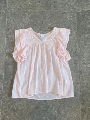 Ljusrosa blus  - Supersöt ljusrosa blus med volangärmar. Blusen har fina spetsdetaljer och är gjord i ett tunt, luftigt tyg. Knappt använd så i väldigt bra skick.