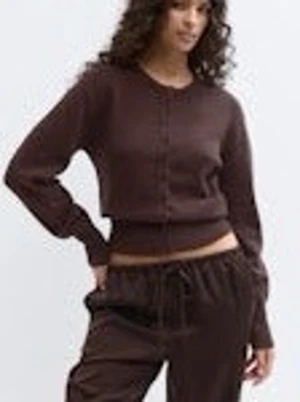Brun stickad kofta - Mysig brun cropped kofta med långa ärmar och knäppning framtill. Tröjan har en enkel, stilren design och ribbade muddar vid ärmslut och midja. Perfekt för en avslappnad och trendig look.