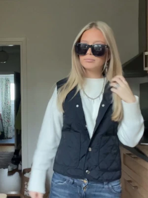 Väst från hm💞⭐️ - Stilren svart dunväst med quiltat mönster och tryckknappar framtill. Västen har två stora fickor och en klassisk krage. Perfekt att slänga över en hoodie eller tröja för en cool lager-på-lager-look.