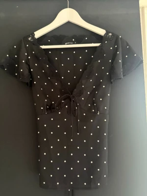 Svart prickig topp - Super fin prickig topp ifrån Gina, man kan knyta åt den både fram till och bak till. I storlek S