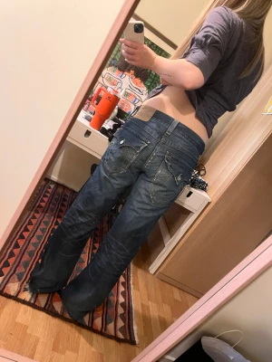 Vintage True religion jeans med hål - Säljer ett par mörkblå bootcut jeans med slitningar från true religion. Står storlek 32. Tror det är herr jeans men skulle säga att alla kan ha dom beroende på hur man vill att dom ska sitta. Kommer inte sälja under 600kr