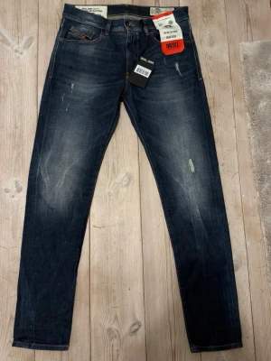 🏔️HELT NYA 🏔️Mörkblå jeans från Diesel - Säljer ett par mörkblå  jeans från Diesel med snygga slitningar och tvättade detaljer. Jeansen har klassisk femficksmodell, gylf med dragkedja och knapp samt kontrastsömmar. Perfekta för en trendig och avslappnad look.