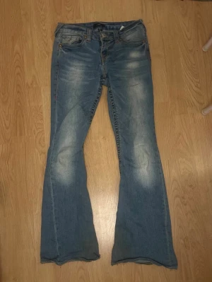 Lowrise True Religon Bootcut  - Lowrise Bootcut jeans från True Religon i modellen Joey. Snygga och trendiga och bra skick. Obs, små slitningar längst ner och lite på fickorna.