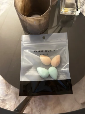 Makeupsvampar i pastell från Lyko - Fyra små makeupsvampar i pastellfärger, två i beige och två i mintgrönt. Svamparna har droppform och kommer i en återförslutningsbar plastpåse. Perfekta för att applicera foundation eller concealer med precision.