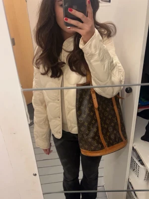 Krämvit pufferjacka från MAG - Säljer en krämvit pufferjacka från MAG i storlek S. Jackan har en quiltad design med rundade sömmar och en kort, boxig passform. Tillverkad i glansigt material som ger en trendig look. Perfekt för att hålla värmen under kyliga dagar.