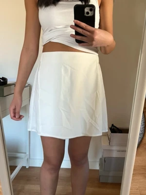Helt ny vit kjol - Säljer en stilren vit kjol från Vero Moda. Kjolen har en elastisk midja för extra komfort. Det är bara baksidan där resåren syns. På bilderna är kjolen skrynklig men den ska egentligen inte vara det, utan man kan stryka den lite. Prislappen är kvar. Den är inte genomskinlig heller 🤍
