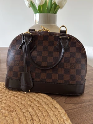 Alma BB  - Säljer min fina Alma BB i Damier Ebene Canvas. Mycket fint skick, aldrig använd 🤍dustbag medföljer. Äkta läder! Pris kan diskuteras vid snabb affär! 