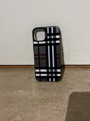Rutigt mobilskal i svart, vitt och rött - Snyggt mobilskal med rutigt mönster i svart, vitt, grått och rött. Skalets design är modern och stilren, perfekt för dig som vill ha ett unikt tillbehör till din mobil. Tillverkat i hårdplast som skyddar mobilen mot repor och stötar.