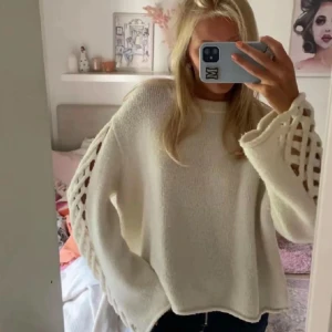 Vit oversized stickad tröja med knutna ärmar - Säljer en ljus beige lite oversized stickad tröja med breda ärmar och dekorativa öppna flätade detaljer längs hela ärmarna. Tröjan har rund halsringning och en mjuk, chunky känsla som passar perfekt för en avslappnad och trendig look. Storlek xs passar s💓💓